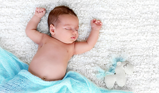 Schlafendes Baby in einer Decke mit Stofftier – Symbolbild für Kinderwunsch und Wunschkind